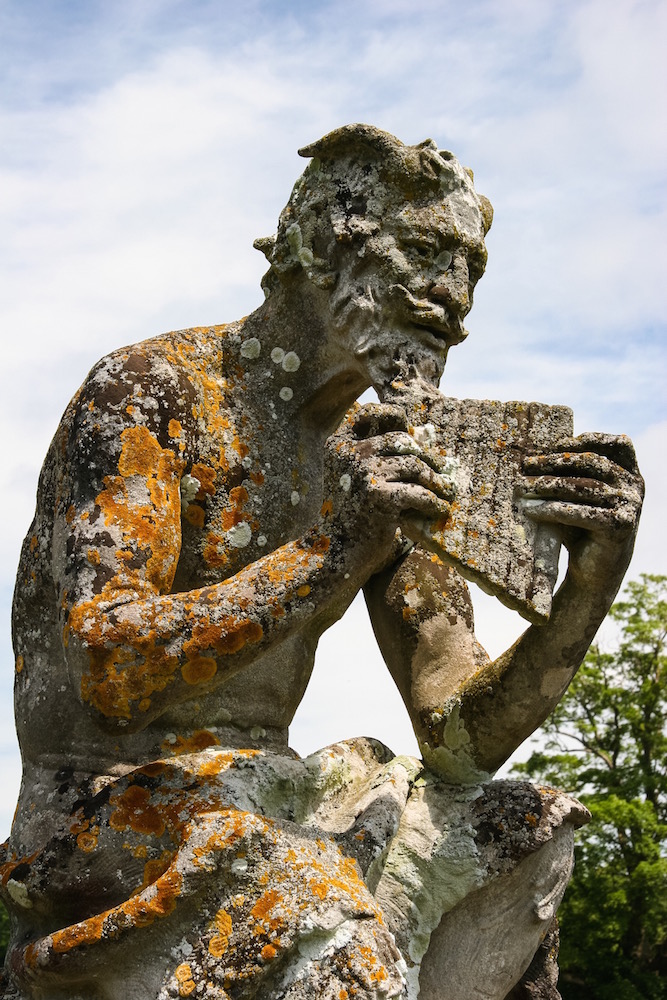 Eine stark bemoste steinerne Statue des Pan