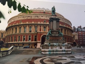 Royal Albert Hall: ein großer, runder Bau aus dunkelen und hellen Steinen. Davor eine Statue