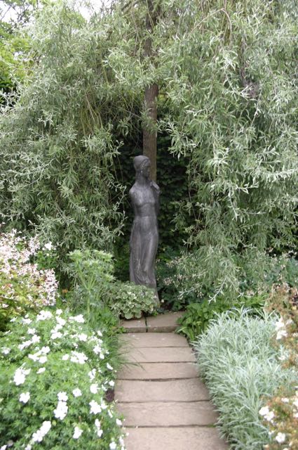 Skulptur einer Frau in der Ecke des Gartens