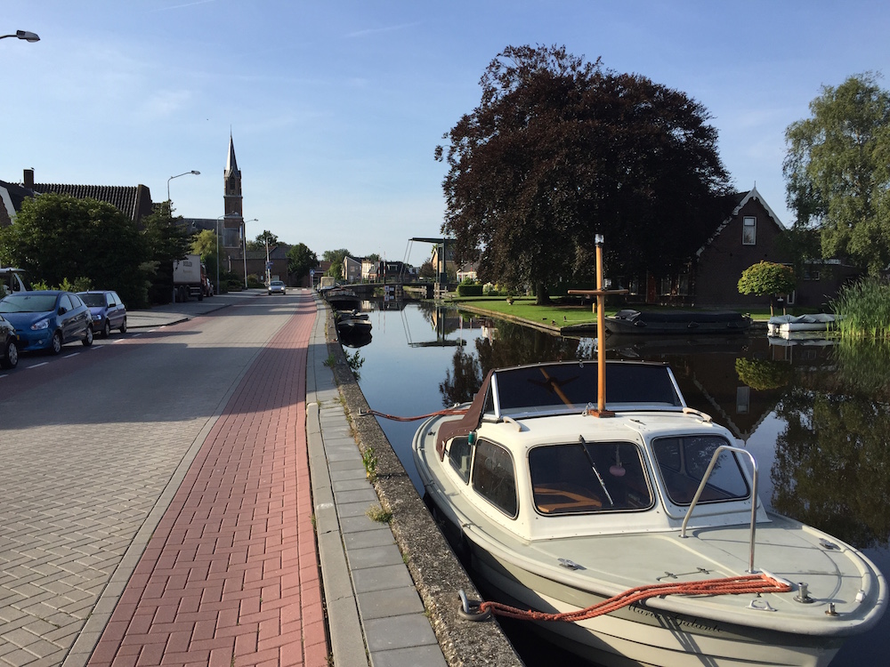 Ein Kanal, eine gepflasterte Strasse, ein Boot im Vordergrund