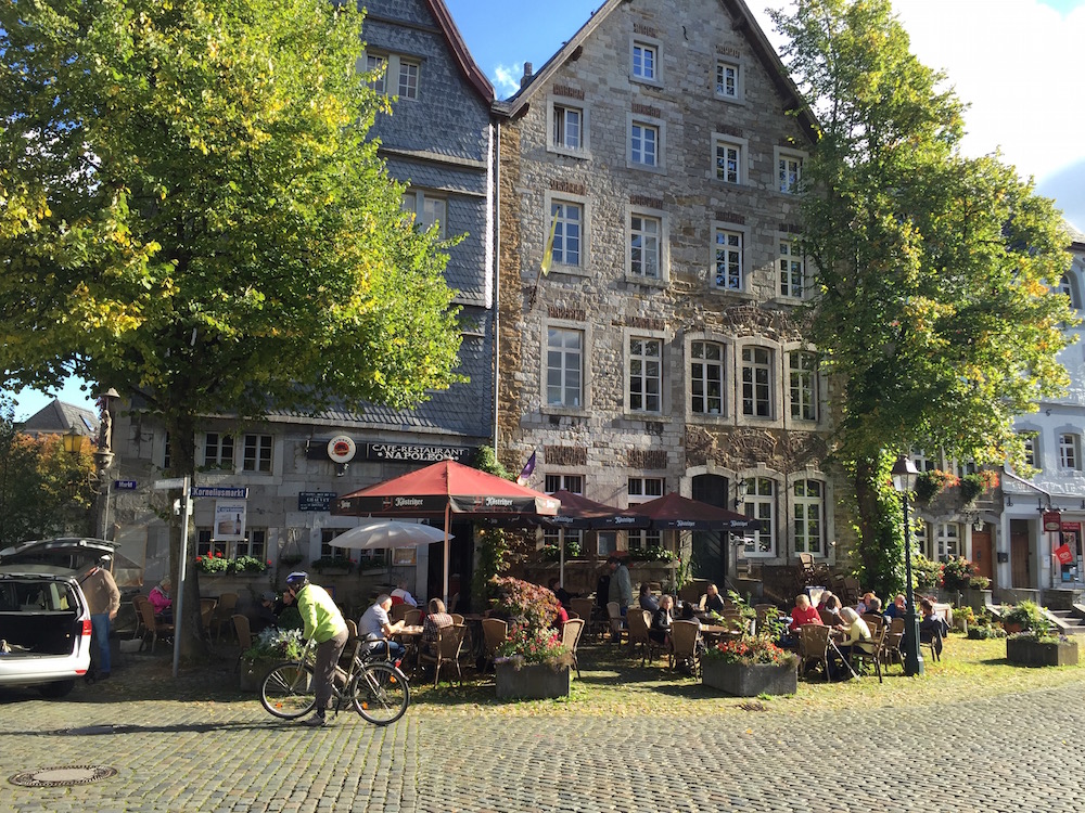 Tische, Stühle und Sonnenschirme vor einem Café