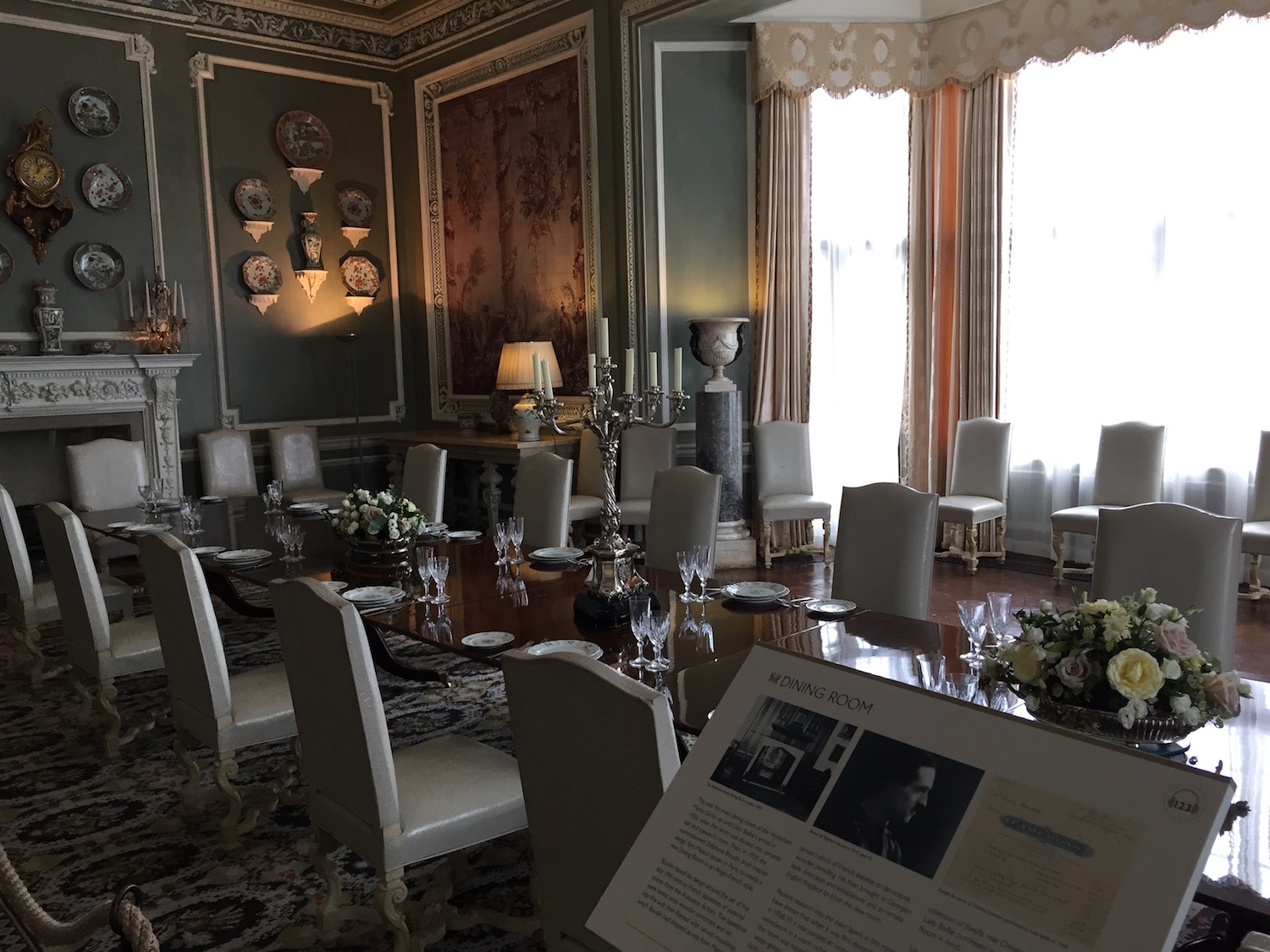 Eine lange Tafel mit hellen Stühlen. An den Wänden hängen Zierteller, rechts lässt ein großes Fenster viel Licht in den Raum