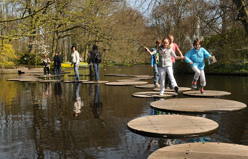 Kinder, die über Platten im See hüpfen