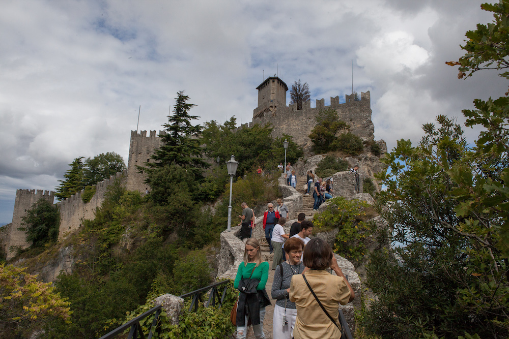 Burg auf Hügel, Menschen die einen Weg hochsteigen